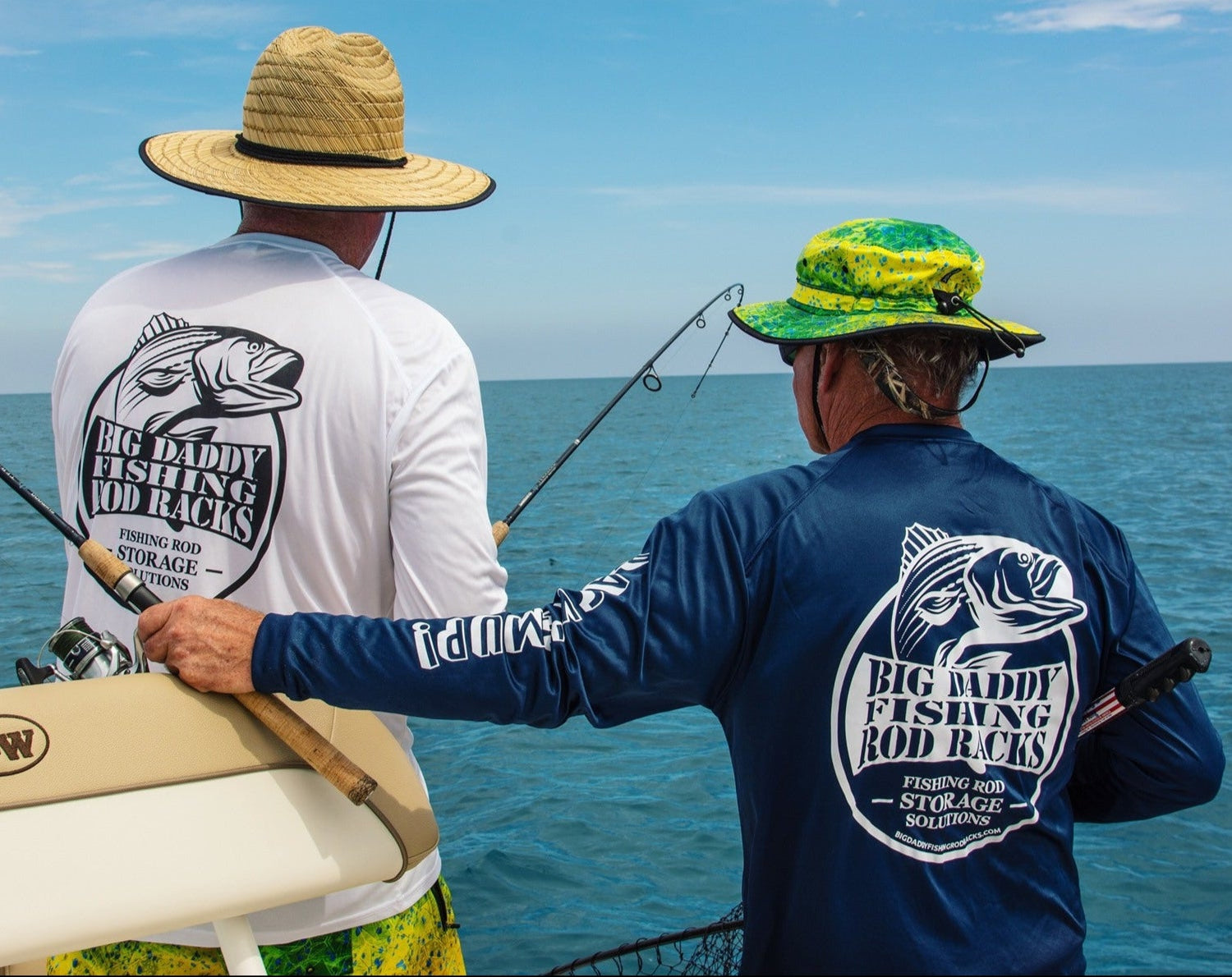 Two people on a boat wearing 'Big Daddy Fishing' shirts with fishing gear, looking out at the ocean.