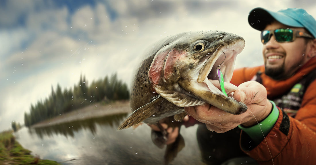 Man holding a salmon in front of a lake