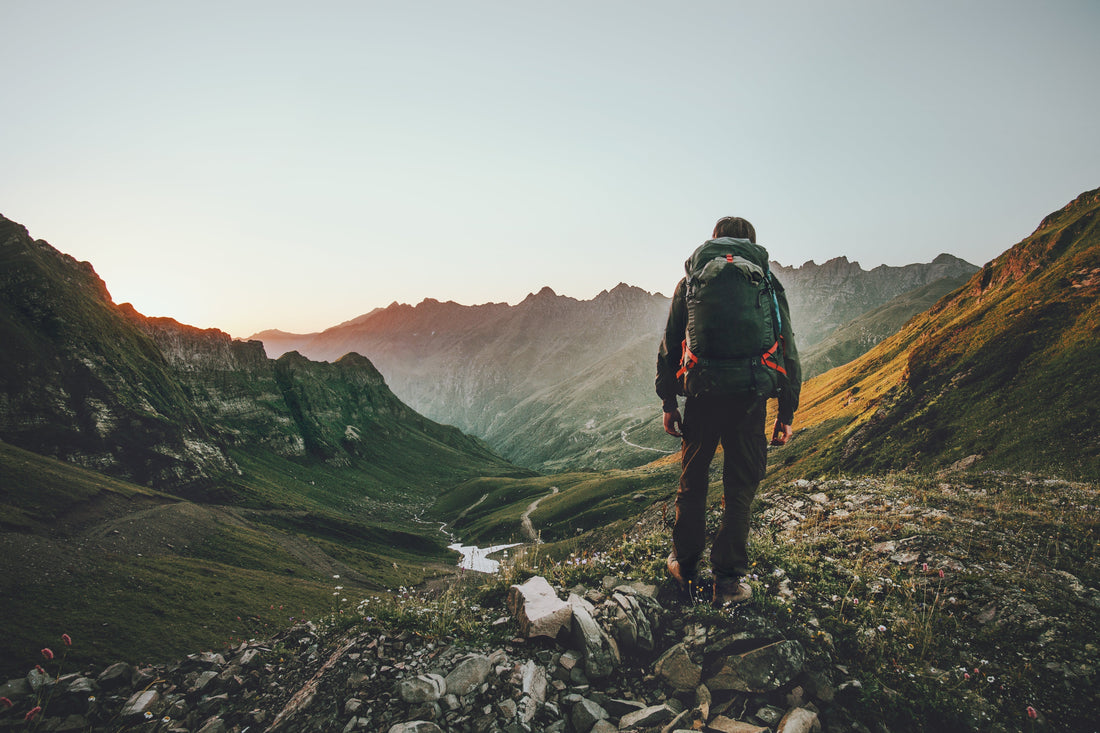 Man hiking at sunset mountains with heavy backpack Travel Lifestyle wanderlust adventure concept summer vacations outdoor alone into the wild