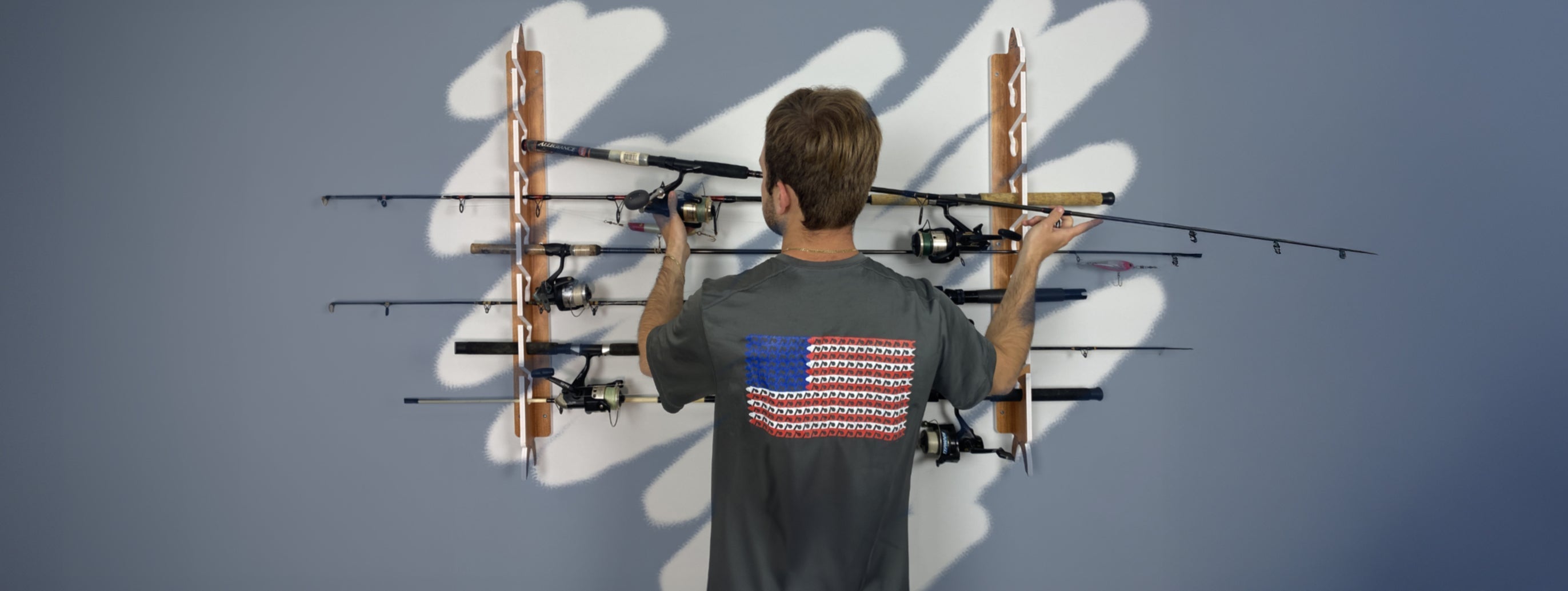 a man handing a fishing pole on a rack thats mounted on the wall