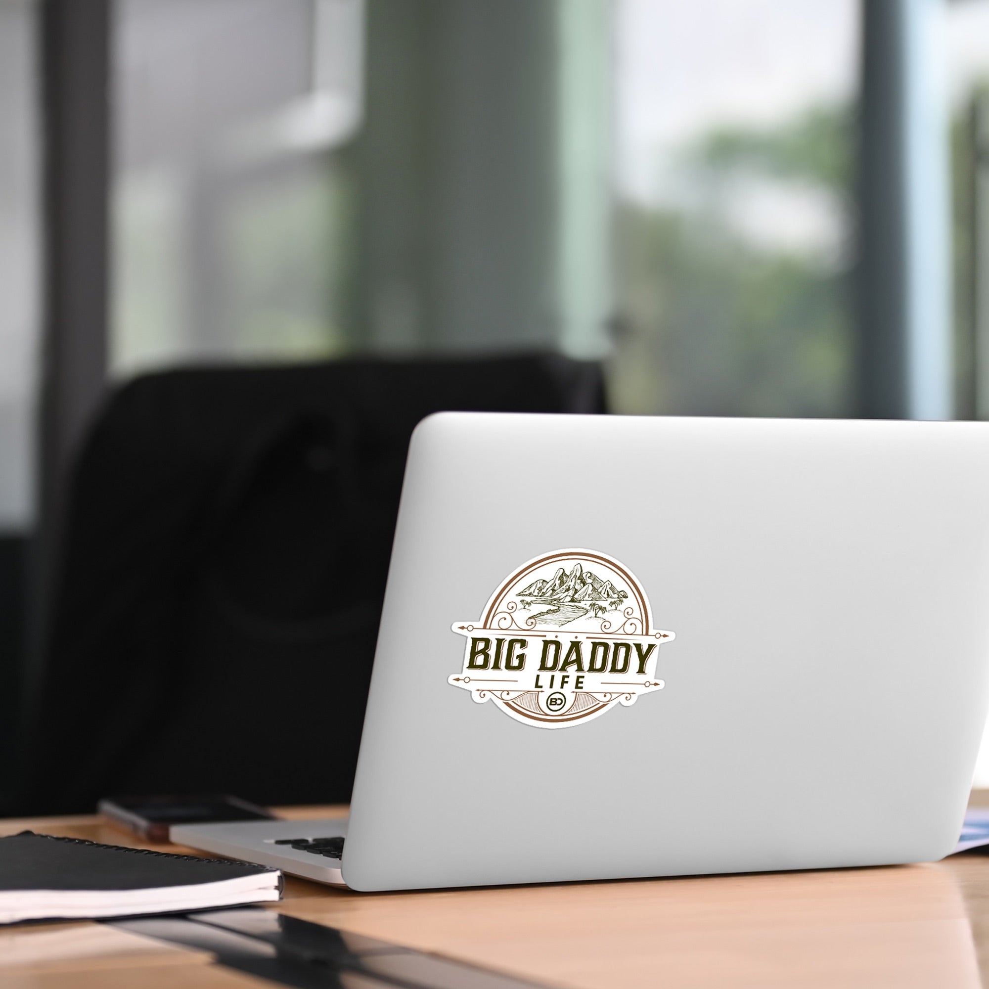 Laptop with 'BIG DADDY LIFE' sticker on a desk in an office setting