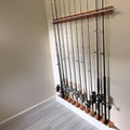 Wall-mounted fishing rod holder with multiple fishing rods against a plain wall.