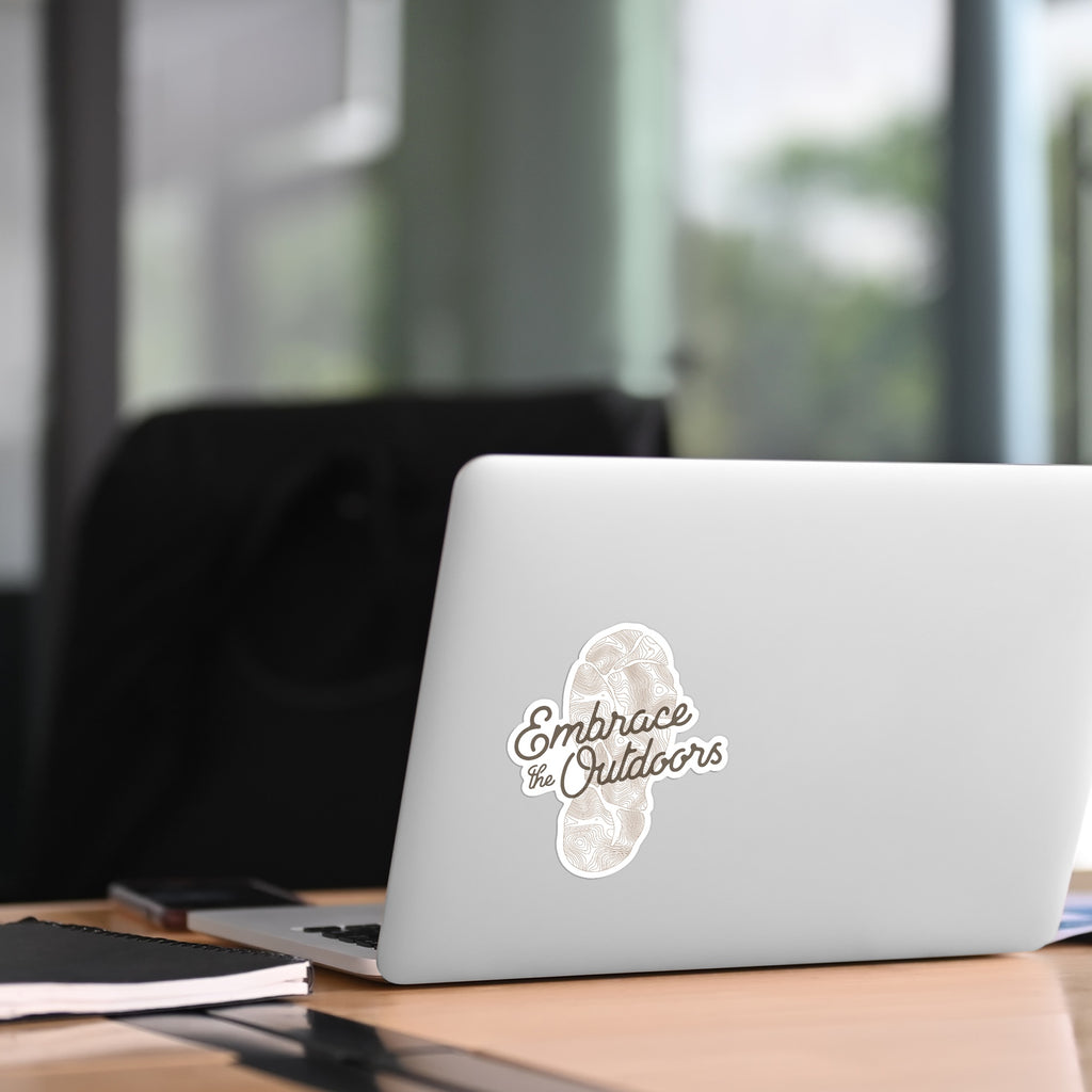 Laptop with 'Embrace the Outdoors' sticker on a desk in an office setting