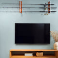 Wall-mounted fishing rod holder with fishing rods above a television on a wooden stand.